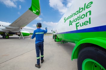 Ground crew refueling airplane with Sustainable Aviation Fuel (SAF) at airport