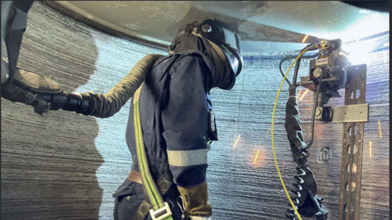 Technician performing automated weld overlay inside a scrubber tower using specialized welding equipment